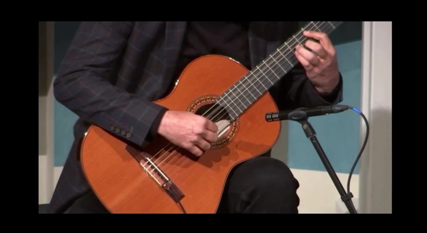 Both hands on the classical guitar mid-phrase