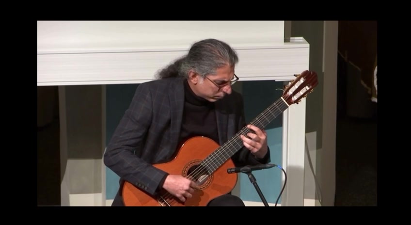 Mohammadali Masjedi in profile, concentrating while playing classical guitar